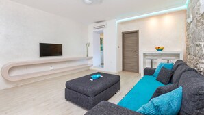 Ein modernes Wohnzimmer mit grauem Sofa, blauem Teppich, flachbildfernseher an der Wand und einer Wand mit Steinverkleidung.