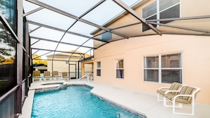 Ein Schwimmbecken mit Glasüberdachung, Liegestühlen und einer Terrasse.