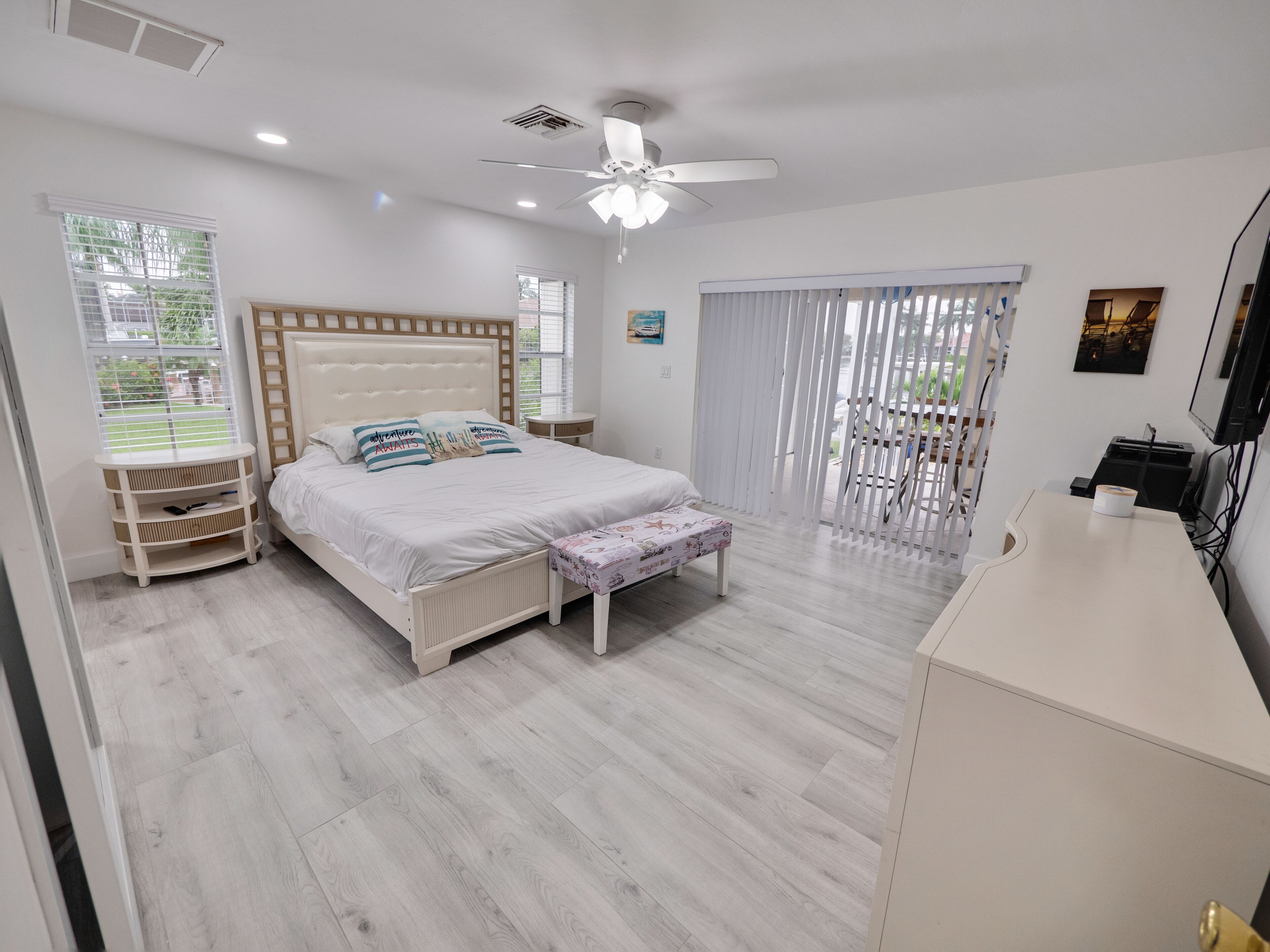 A bedroom with a bed, bedside tables, a ceiling fan, and a TV.