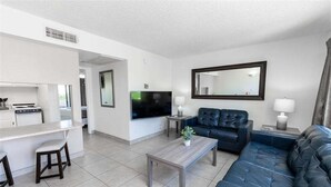 Ein modernes Wohnzimmer mit Sofa, Couchtisch, Fernseher und Küchenzeile.
