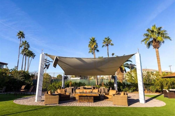 An outdoor seating area with a canopy, wicker furniture, and palm trees.