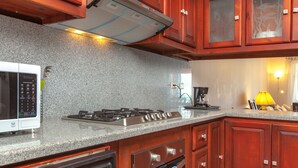 Eine Küche mit Granitarbeitsplatten, Holzschränken, einer Mikrowelle, einem Herd, einem Backofen und einer Kaffeemaschine.
