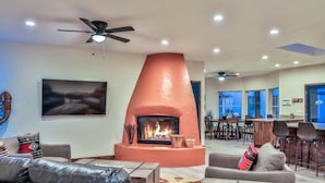 A living room with a fireplace, leather sofas, a ceiling fan, and a dining area in the background. - Sleeps 23: Luxury Retreat with Pool/Hot Tub, Casitas, Pet-Friendly, Near Riviera Marina (Lake Havasu City)