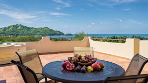 A round table with a fruit bowl and chairs on a terrace overlooking a scenic view. - PRIVATE ROOFTOP, HILLTOP PANORAMIC OCEAN-VIEW CONDO. COCO SUNSET HILLS, CR. (playas del coco)