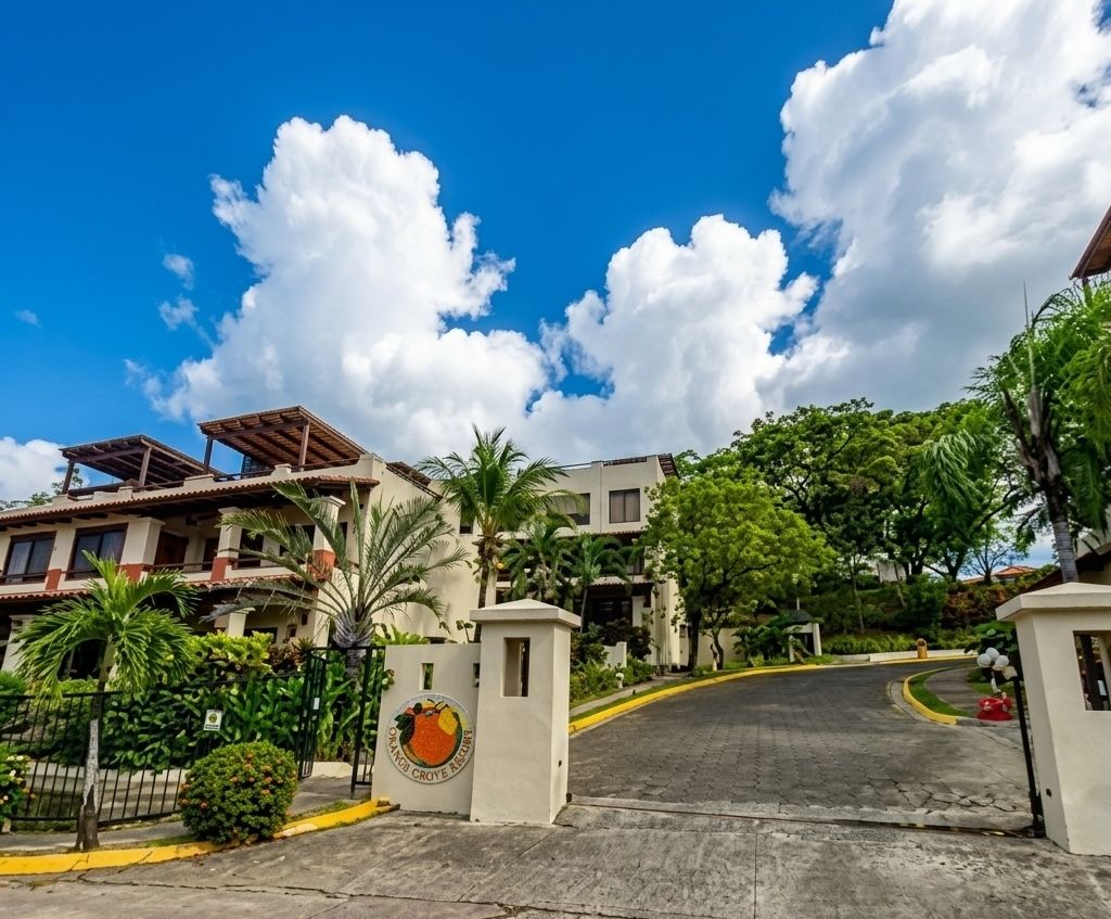 A gated entrance to a residential area with a clear sky and lush greenery.