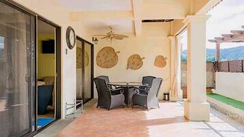 Une terrasse extérieure avec une table et des chaises, un ventilateur de plafond et des éléments décoratifs sur les murs.