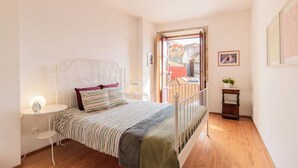Une chambre à coucher avec un lit, une table de chevet, une lampe et une vue sur l’extérieur.