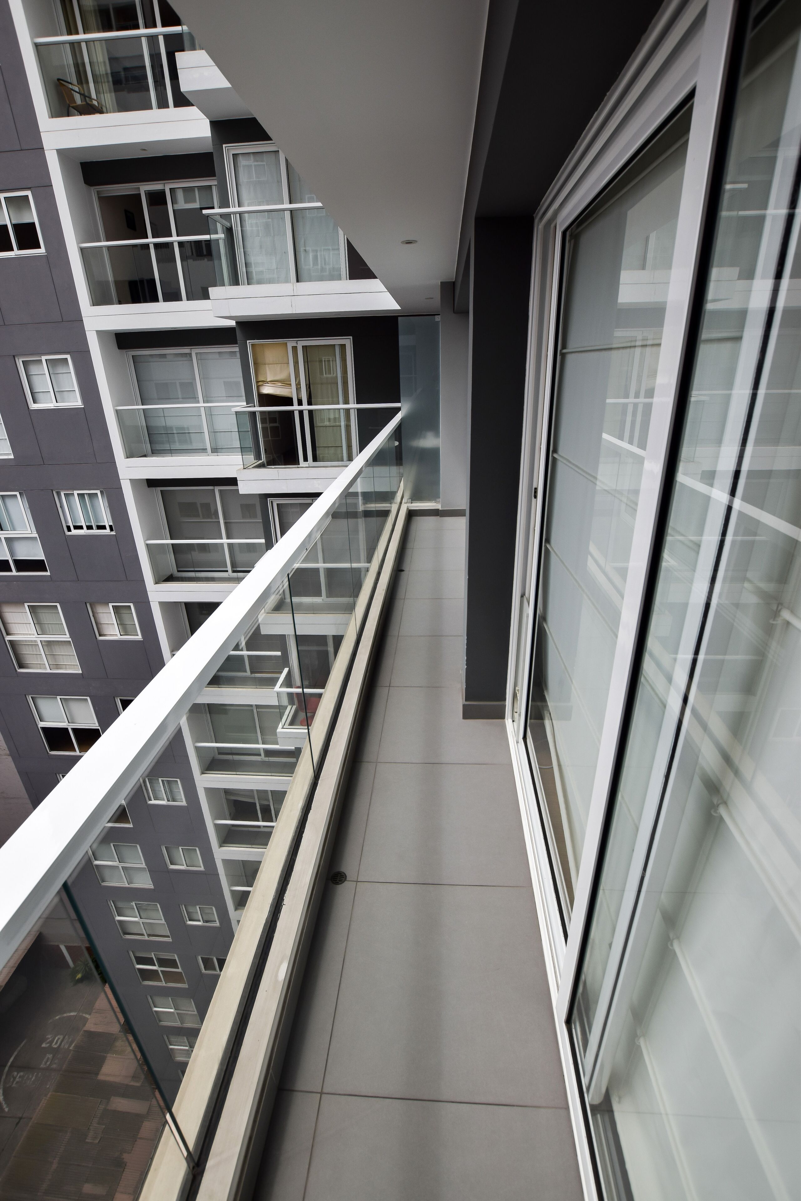 Ein modernes Gebäude mit Glasgeländer, gefliestem Boden und einem großen Fenster.