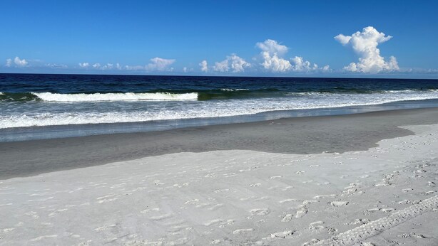 Ein Strand mit blauem Himmel und Meereswellen.