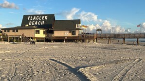Ein Strandhaus namens 'Flagler Beach' mit einer Holzterrasse und einem Steg, der ins Meer führt.