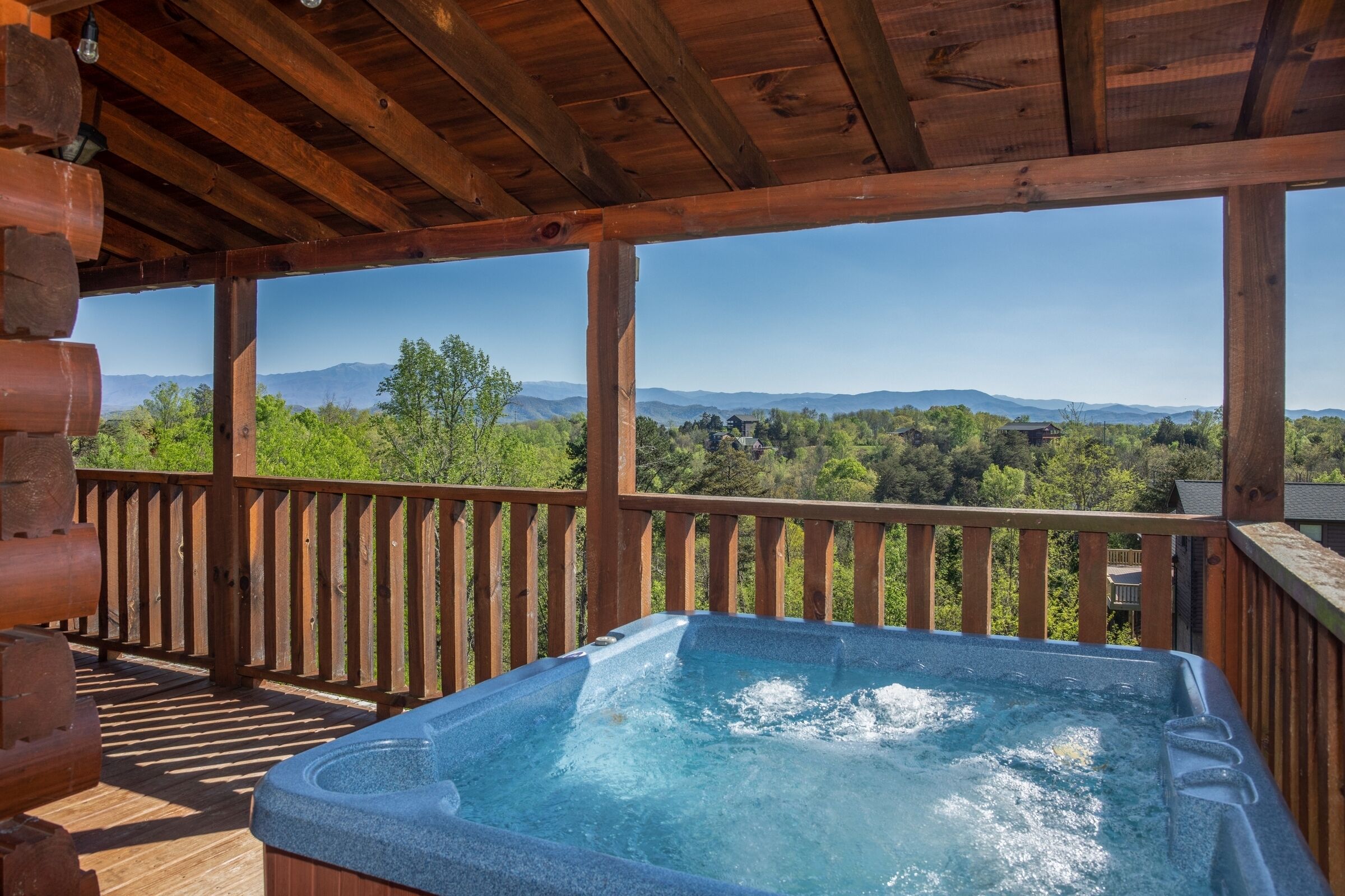 Um deck de madeira com hidromassagem e vista para montanhas.