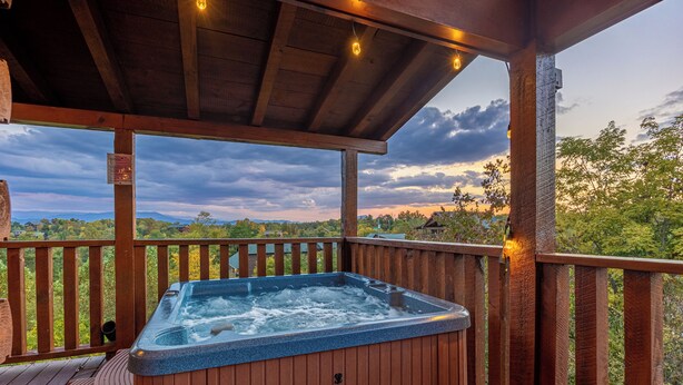 A wooden deck with a hot tub, wooden railings, and a view of the landscape. - Smoky Mountain Lodge | 6 King Suites, Hot Tub, Views, Game Room, flat entry (Sevierville)