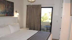 Een hotelkamer met een groot bed, een kleintje tafeltje en uitzicht op buiten.