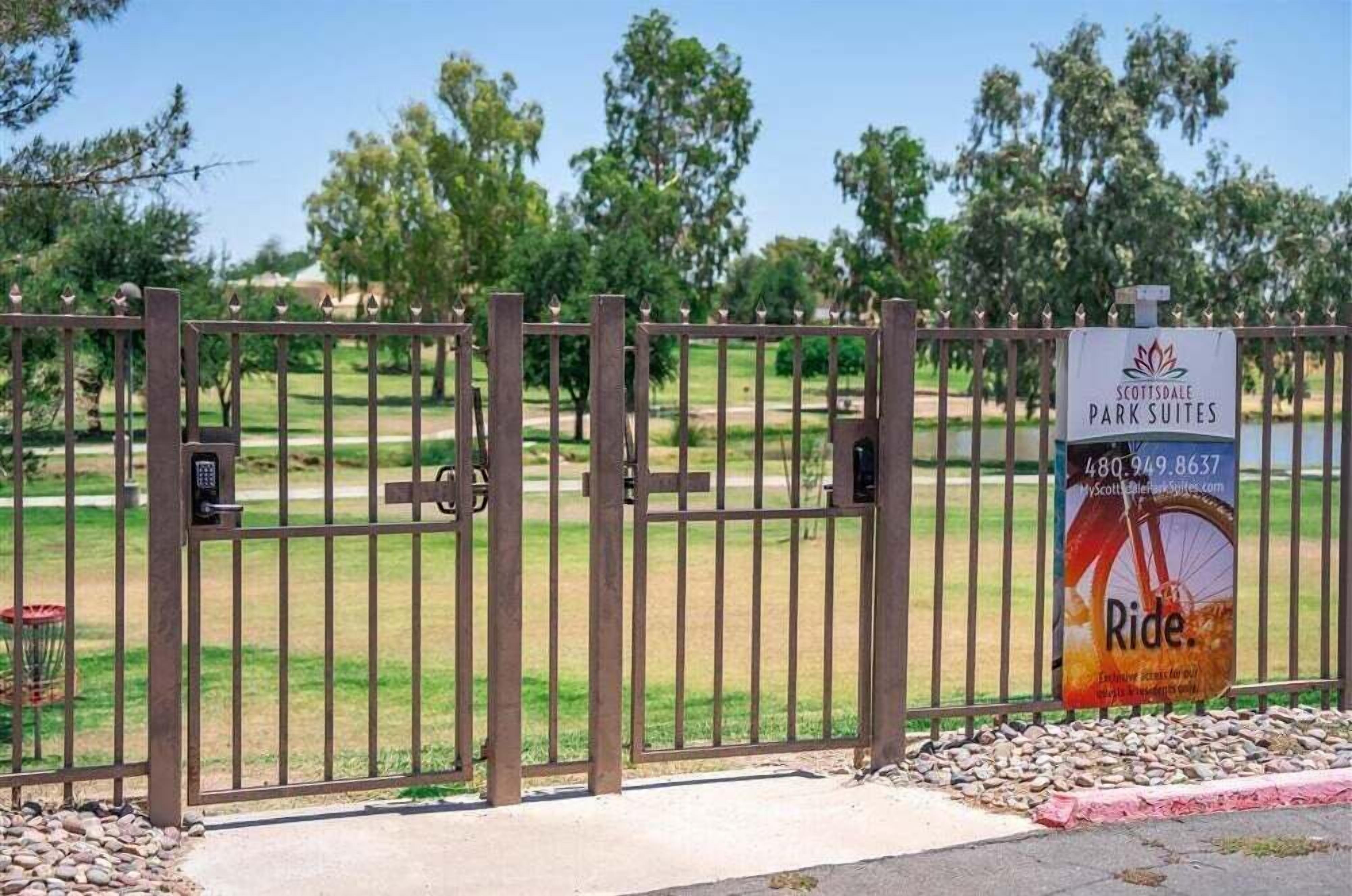 Een omheind toegangspunt naar Scottsdale Park Suites, met een bord waarop de accommodatie wordt aangeboden.