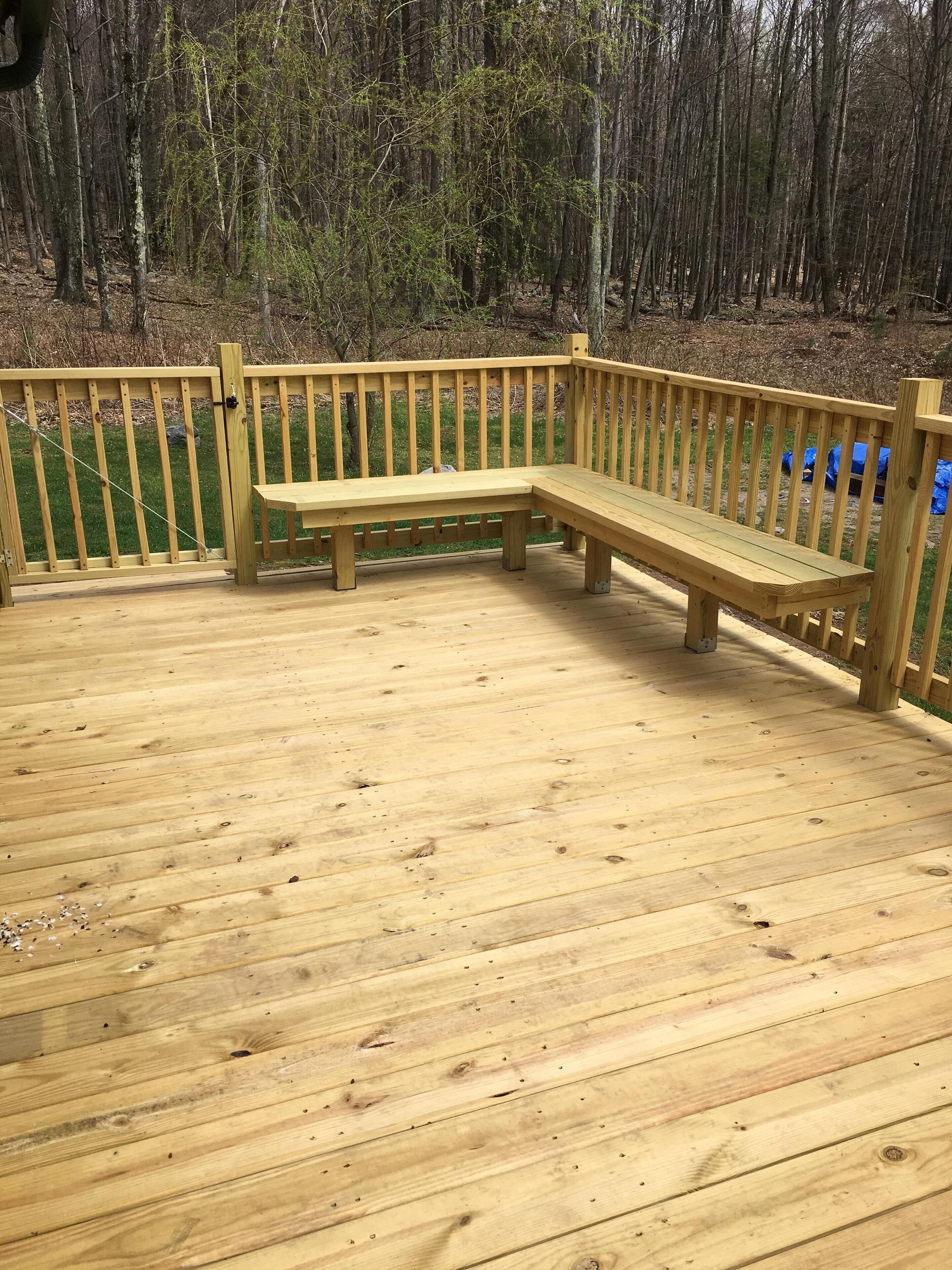 A wooden deck with a bench and a railing.