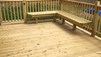 A wooden deck with a bench and a railing.
