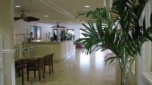 A spacious hotel lobby with a dining area, a reception desk, and a large potted plant. - Waikiki Grand Across from Waikiki Beach & Zoo in the heart of Waikiki! (Honolulu)