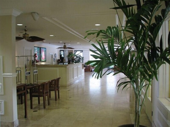 En rymlig hotellobby med en matplats, en receptionsdisk och en stor krukväxt.