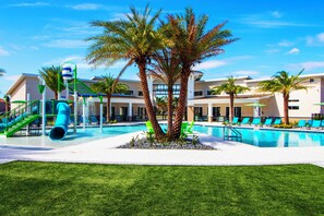 A pool area with palm trees, a water slide, and lounge chairs.