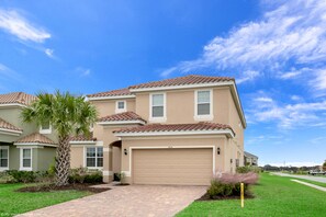 A two-story house with a beige exterior, a brown tiled roof, and a garage.