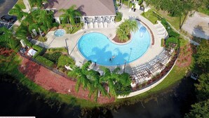 Vue aérienne d’un complexe hôtelier doté d’une grande piscine, d’un patio couvert et d’un aménagement paysager luxuriant.