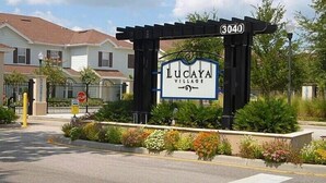 Une entrée fermée par un portail mène au village de Lucaya, et une plaque indique l’adresse : 3040.
