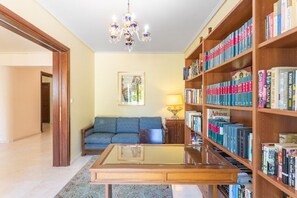 Ett bibliotek med bokhyllor, en soffa, ett soffbord och en kristallkrona.