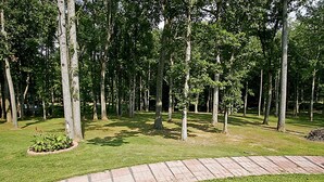 A park with a paved walkway, surrounded by tall trees and grassy areas. - Nice Quiet Family Home - Long Term (Potomac)