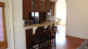 A kitchen with wooden cabinets, a granite countertop, and two bar stools. - Nice Quiet Family Home - Long Term (Potomac)