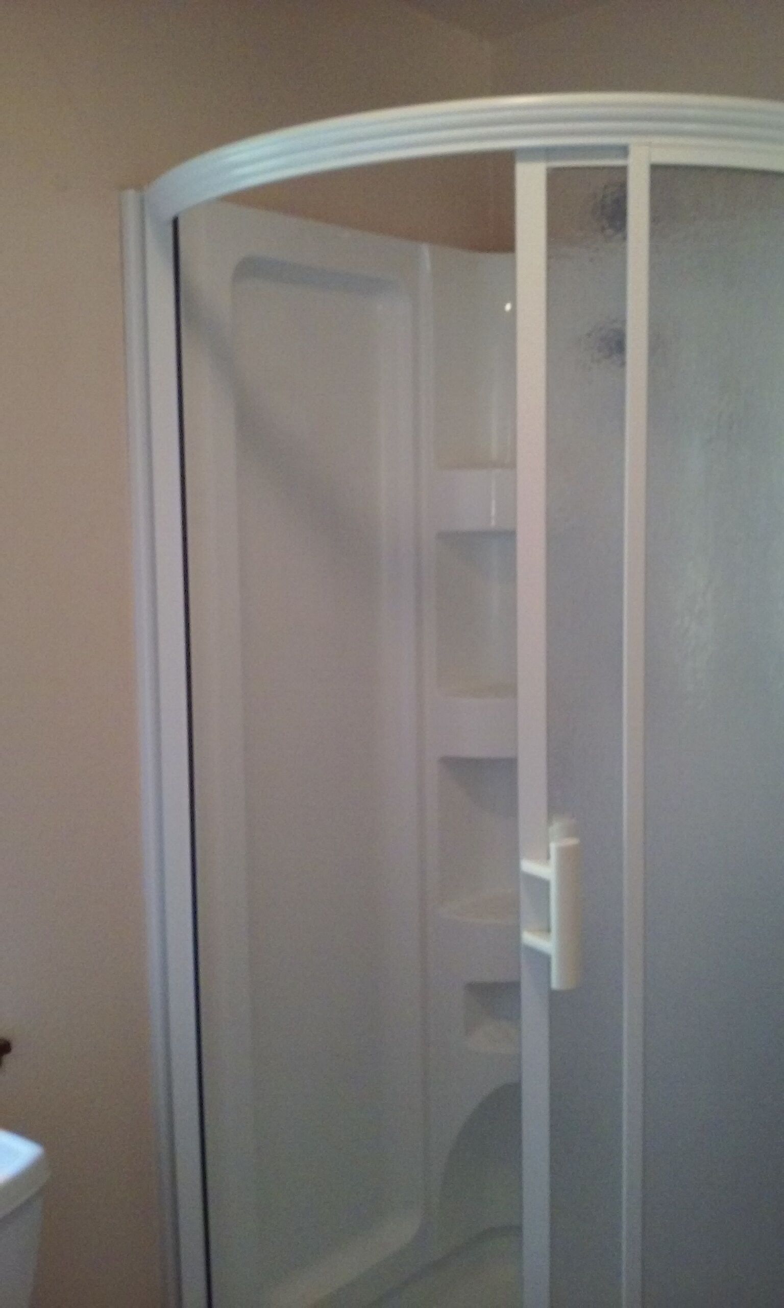 A bathroom with a glass shower enclosure, a toilet, and a white sink.