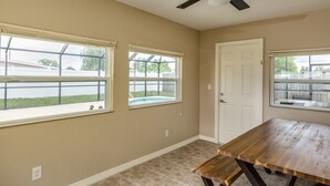 A room with a ceiling fan, two windows with blinds, a door, and a wooden table. - Downtown home, sleeps 6, pool, free WiFi, walk to Library, Doc's, Eatery (Port Charlotte)