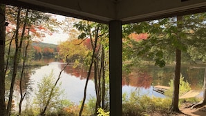 Une vue depuis une fenêtre donnant sur un lac entouré d’arbres aux feuilles d’automne.