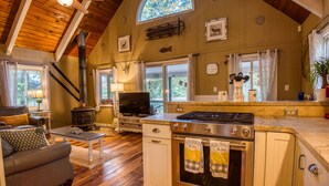 L’intérieur d’un chalet accueillant, avec une cheminée, un plafond en bois et une grande fenêtre.