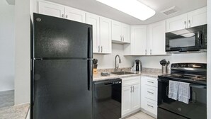 A kitchen with white cabinets, a black refrigerator, a microwave, and a stove. - 141 Fully Furnished, WiFi Included! (Scottsdale)