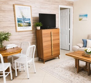 Una sala de estar con un mueble de madera, un televisor, una mesa de comedor con sillas y un sofá.