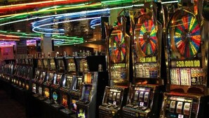 A row of slot machines with illuminated reels and a neon-lit ceiling.