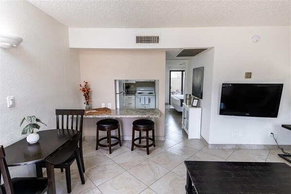 A compact living space with a kitchen, dining area, and a TV mounted on the wall. - Your Home Away from Home in Scottsdale 119 (Scottsdale)