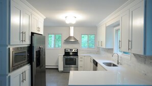 Una cocina moderna con armarios blancos, electrodomésticos de acero inoxidable y una isla grande con pileta.