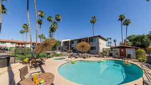 A swimming pool with lounge chairs and umbrellas, surrounded by palm trees and a building. - 137 -Amazing Views-The Perfect Scottsdale Stay (Scottsdale)