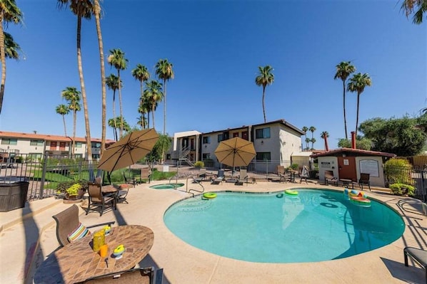 A swimming pool with lounge chairs and umbrellas, surrounded by palm trees and a building. - 137 -Amazing Views-The Perfect Scottsdale Stay (Scottsdale)