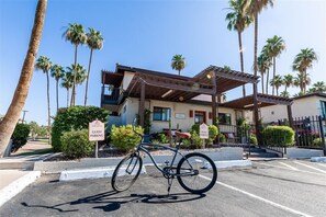 A building with a covered parking area, palm trees, and a bicycle parked in front. - 137 -Amazing Views-The Perfect Scottsdale Stay (Scottsdale)