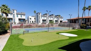 A tennis court with a net, surrounded by a fence, and adjacent to a building with multiple windows and balconies. - 137 -Amazing Views-The Perfect Scottsdale Stay (Scottsdale)