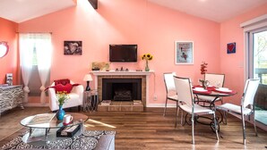 A living room with a fireplace, a dining area with a table and chairs, a TV mounted on the wall, and a window with curtains. - View, 1 King bed & sleeper; .33 mi to Barton Springs/Zilker Park, @2 mi to DT! (Austin)