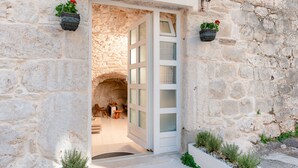 Un bâtiment en pierre avec une porte blanche donnant sur un intérieur comprenant une table et des chaises.