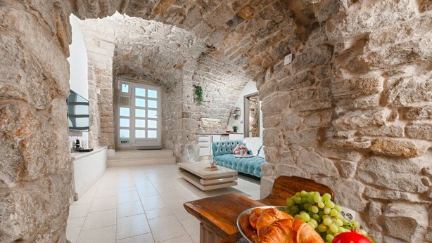 Une pièce aux murs de pierre, avec une table en bois, un canapé et une vue par la fenêtre.
