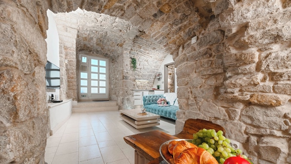 Une pièce aux murs de pierre, avec une table en bois, un canapé et une vue par la fenêtre.