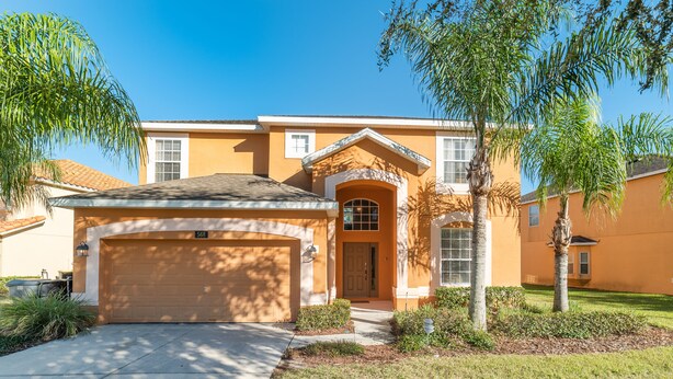A residential house with a garage, a front door, and a well-maintained lawn with palm trees. - Serene Pool Home Overlooking Conservation Area 🌳🏊‍♂️ (Davenport)