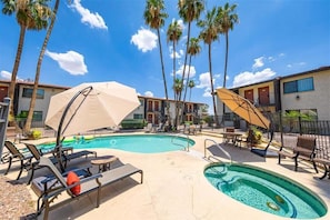 A pool area with lounge chairs, umbrellas, and palm trees. - 239-One Bedroom, Pool, Hot Tub, Putting Green (Scottsdale)