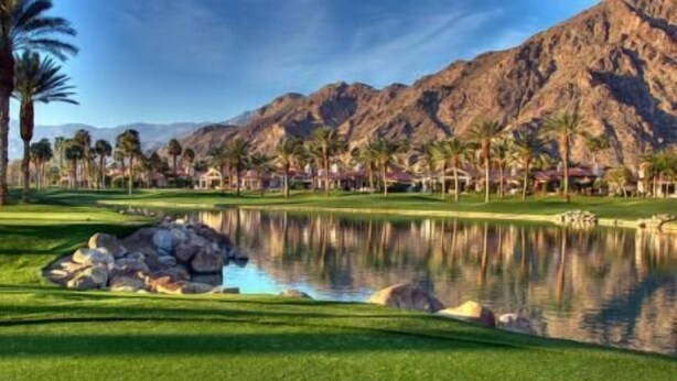 A golf course with a pond, palm trees, and mountains in the background. - 239-One Bedroom, Pool, Hot Tub, Putting Green (Scottsdale)