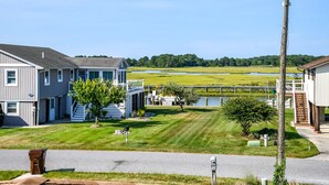 A residential area with houses, a grassy lawn, a small pond, and a dock.